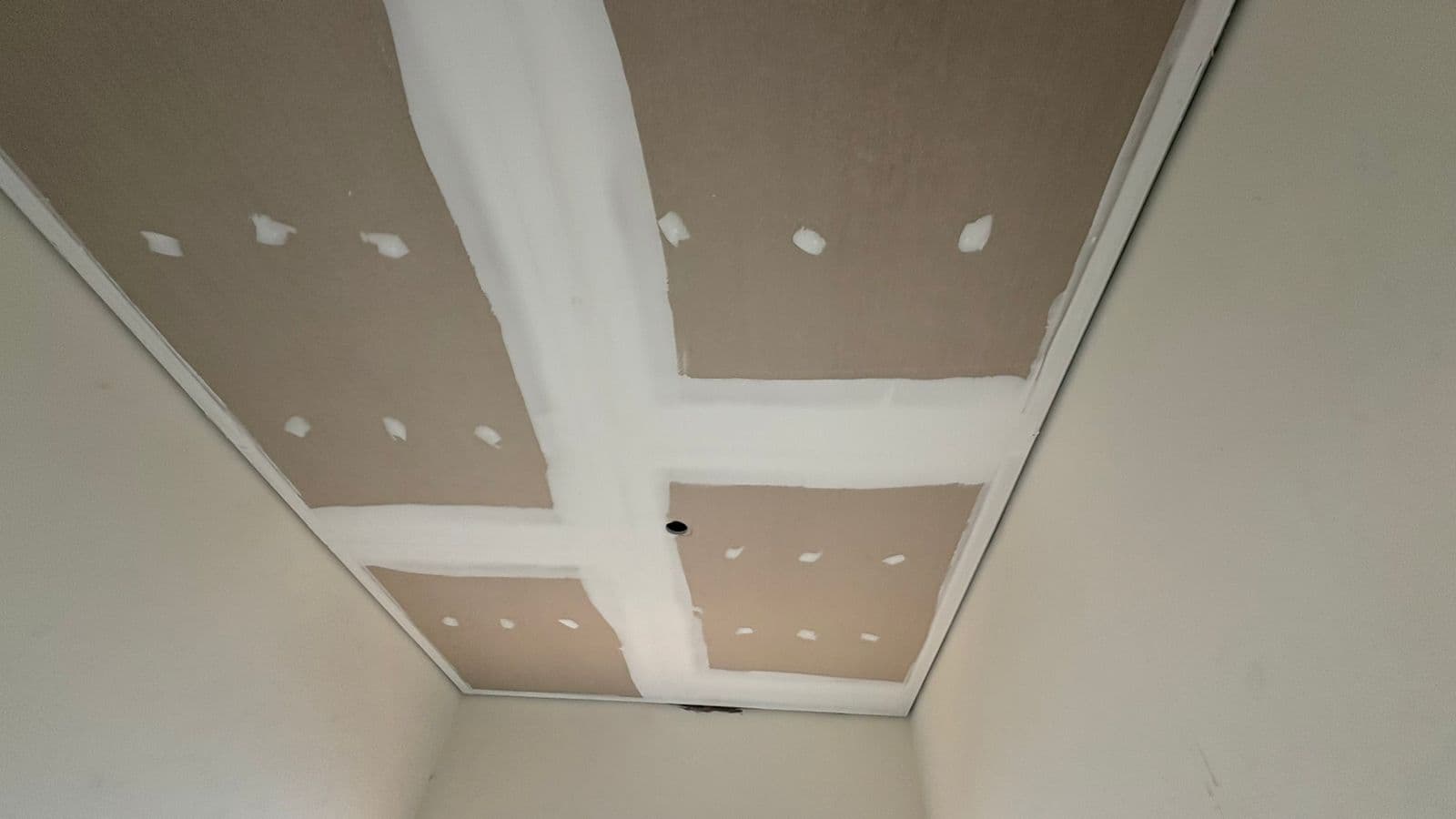 Acabamento de forro em gesso durante a fase final da obra